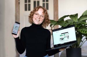 Lisann Bach von neuland21 zeigt die Klimadaten-Plattform der Stadt Bad Belzig auf Laptop und Smartphone